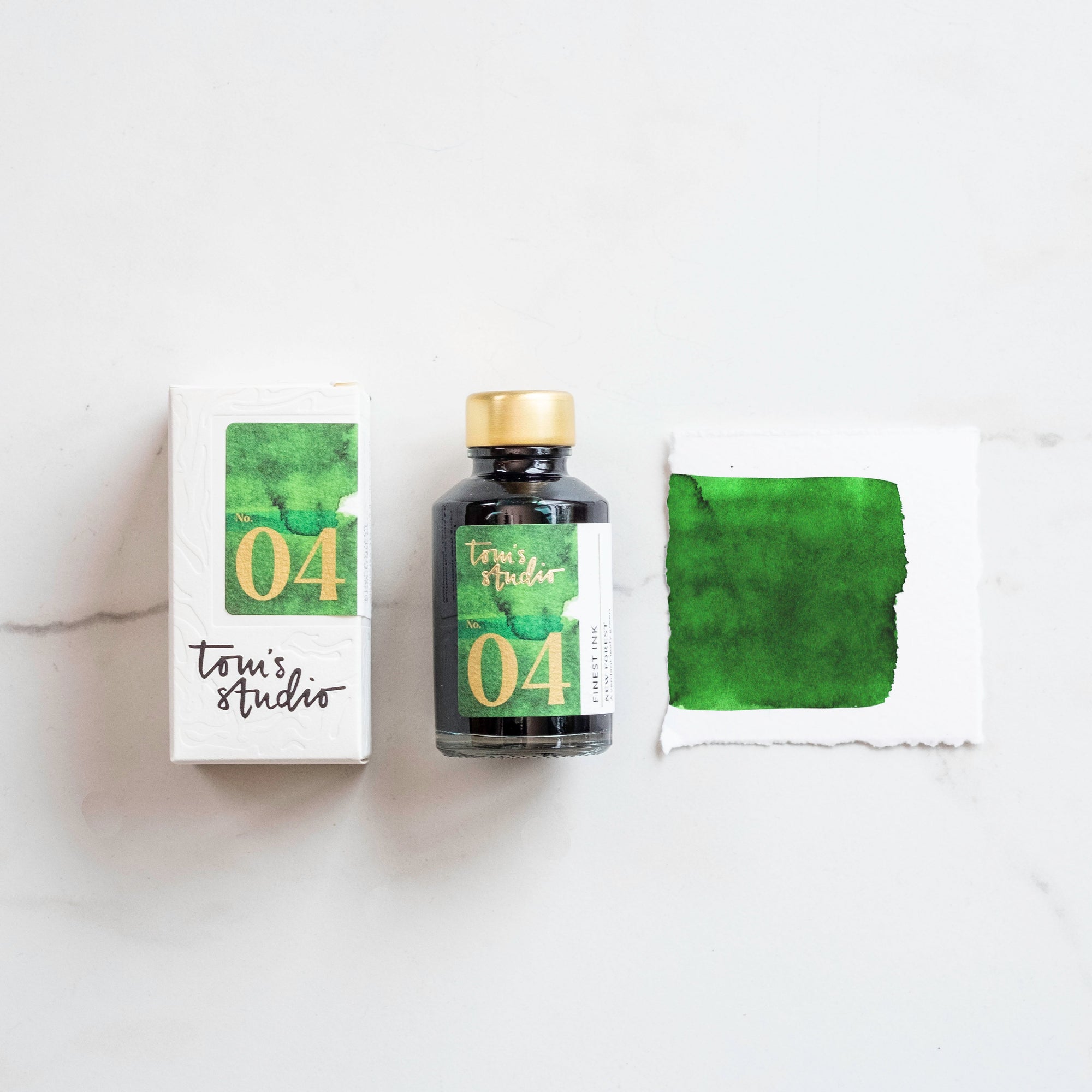 Tom's Studio New Forest Green Fountain Pen Ink with two pens with inky goodness on paper with an ink swatch demonstrating the colour