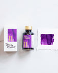Tom's Studio Iris Fountain Pen Ink with two pens with inky goodness on paper with an ink swatch demonstrating the colour