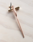 butterfly brass pen rest with a rose gold pen on it