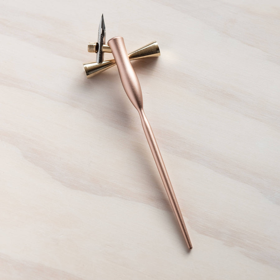 butterfly brass pen rest with a rose gold pen on it