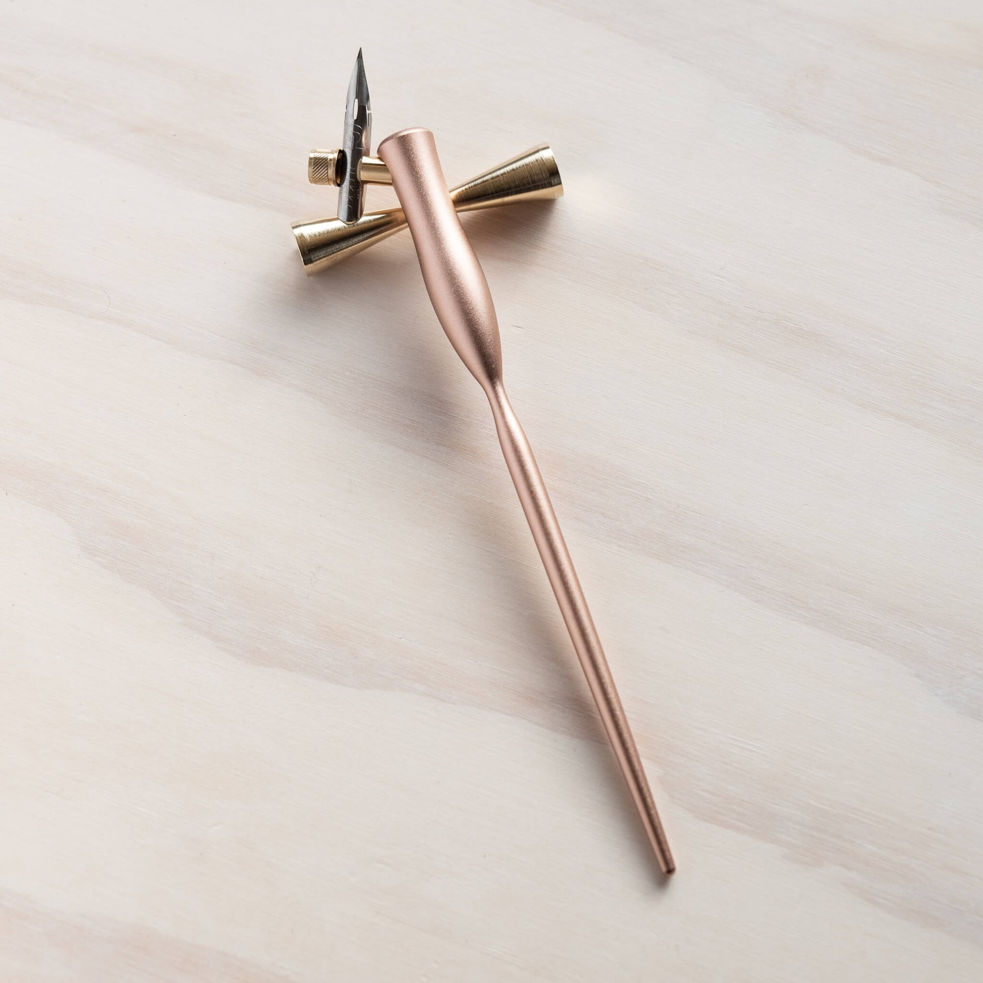 The butterfly brass pen rest with a rose gold oblique calligraphy pen on it