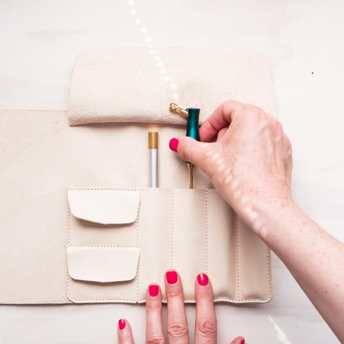 A calligrapher removing an oblique calligraphy pen from the handmade leather pen roll