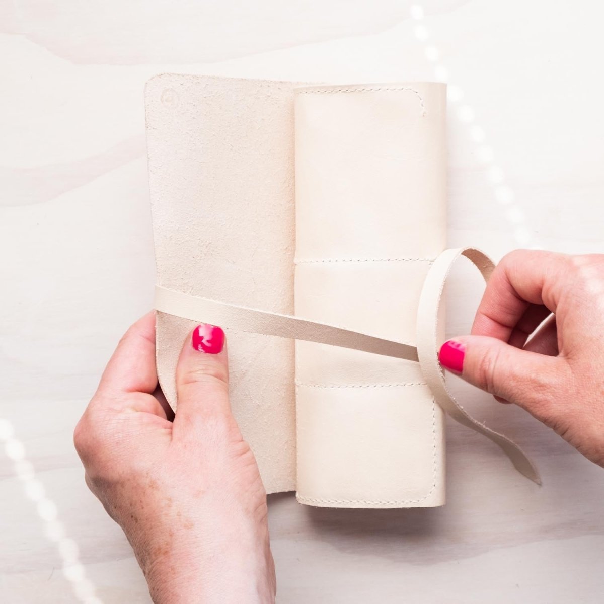 Hands tying up the handmade leather pen roll