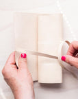 Hands tying up the handmade leather pen roll