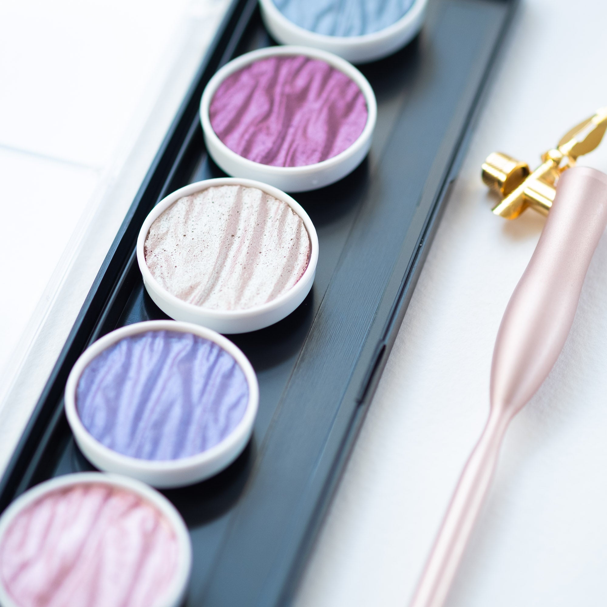 close up of a Fairytale Metallic Finetec Ink Palette on a white desk with an oblique calligraphy pen