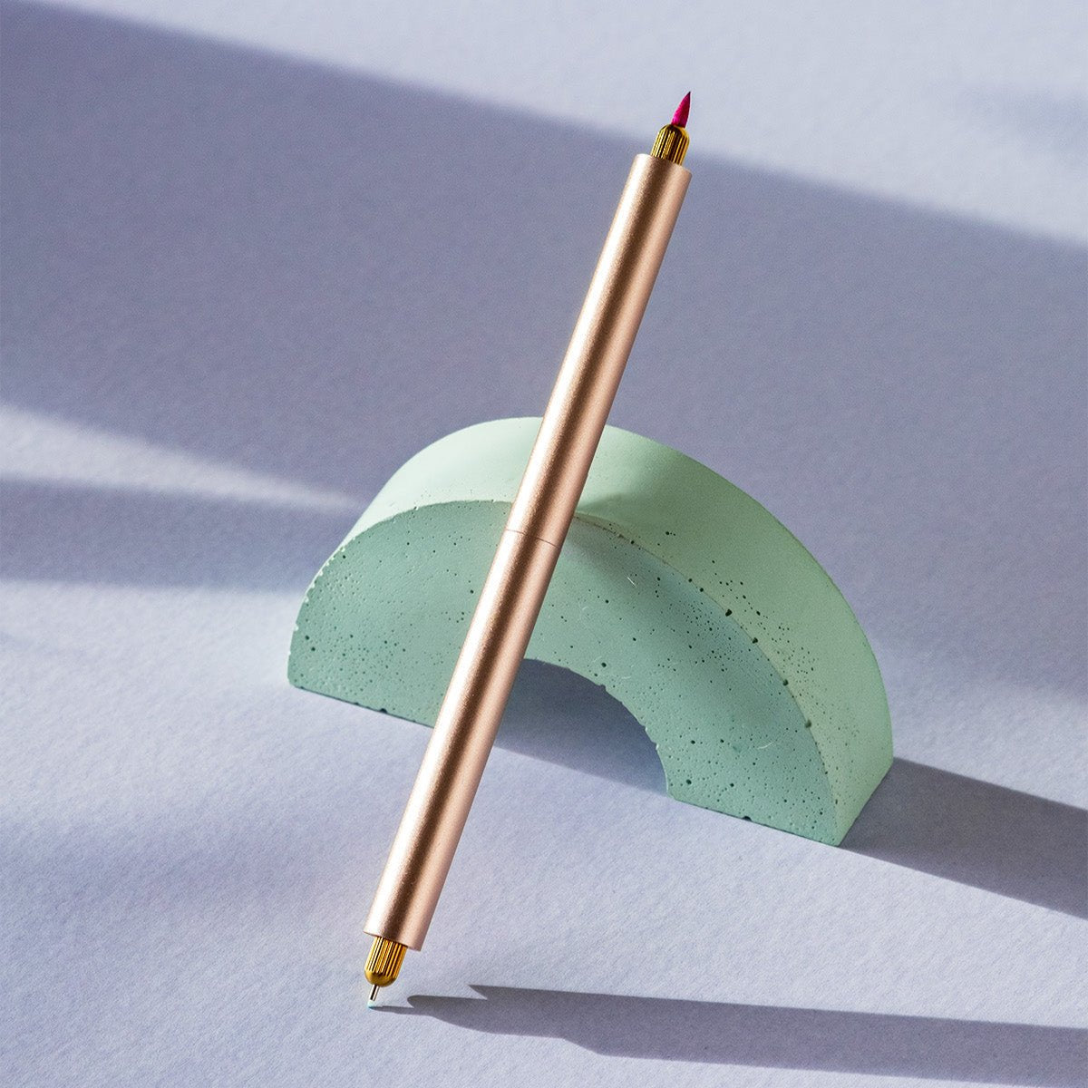 the lumos duo refillable fineliner in rose gold on a green arch with a brush tip