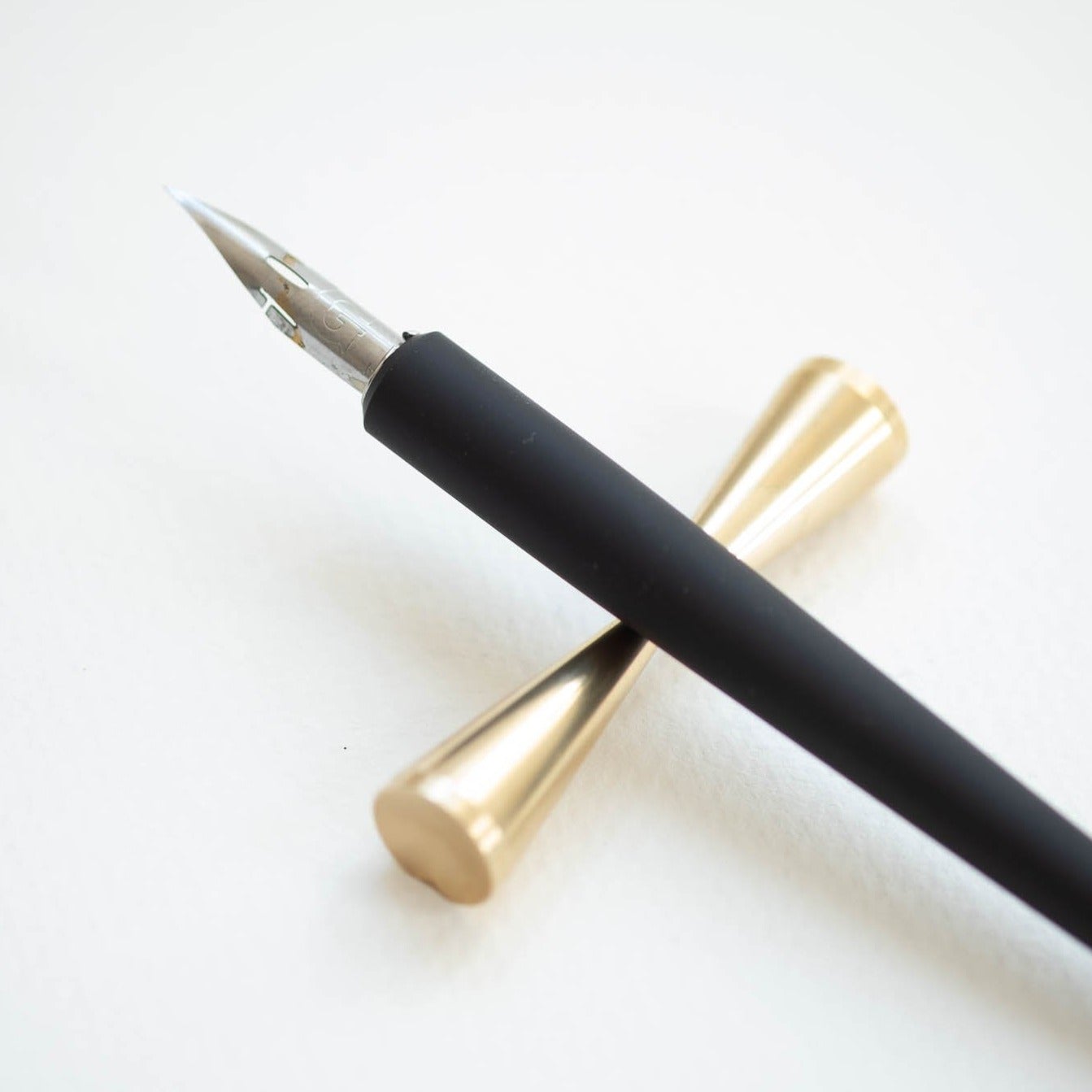 The Original Flourish Straight Calligraphy Pen in Black shown on the Butterfly Brass Pen Rest