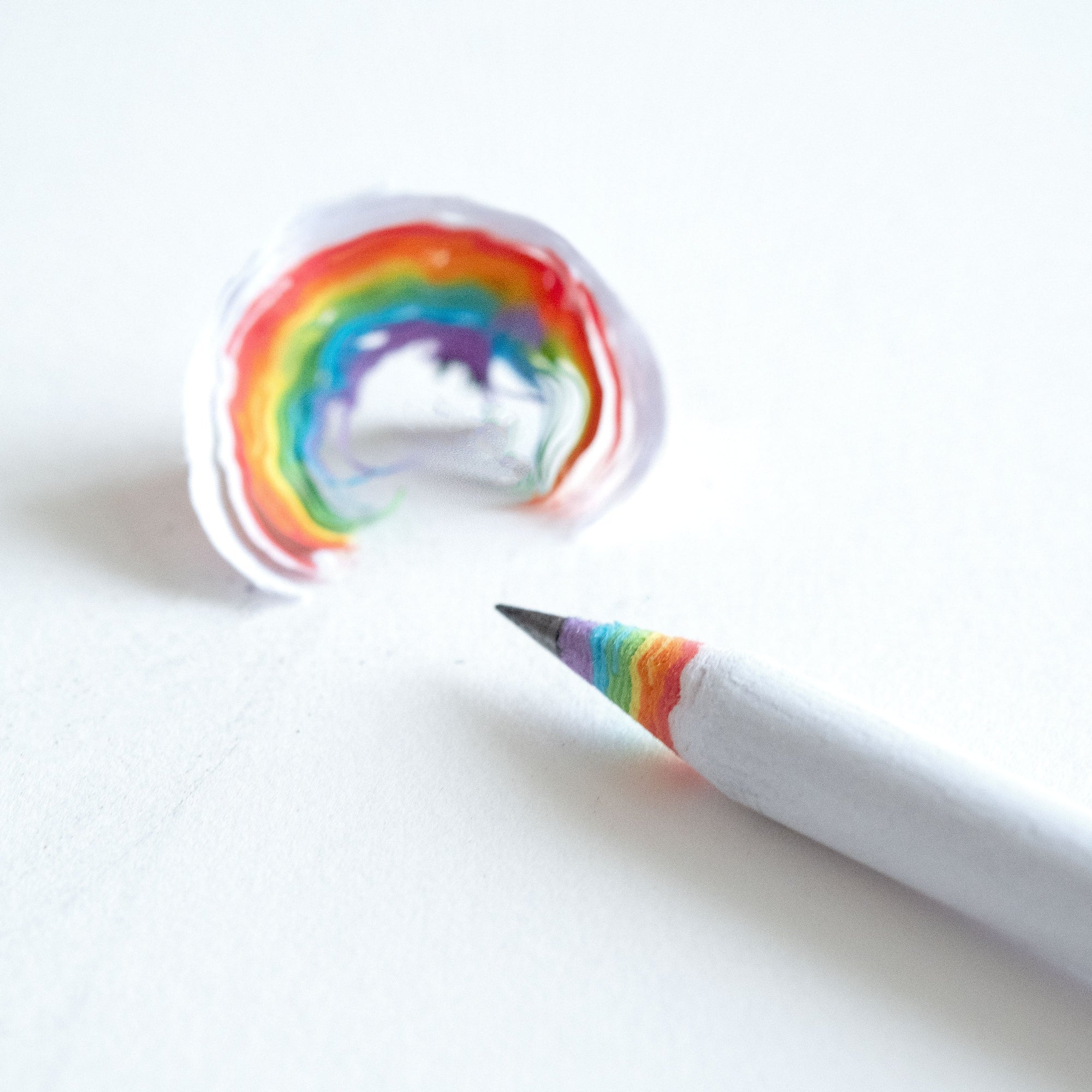 Rainbow pencil close up with a sharpened lead and a wood shaving fro the pencil showing the rainbow