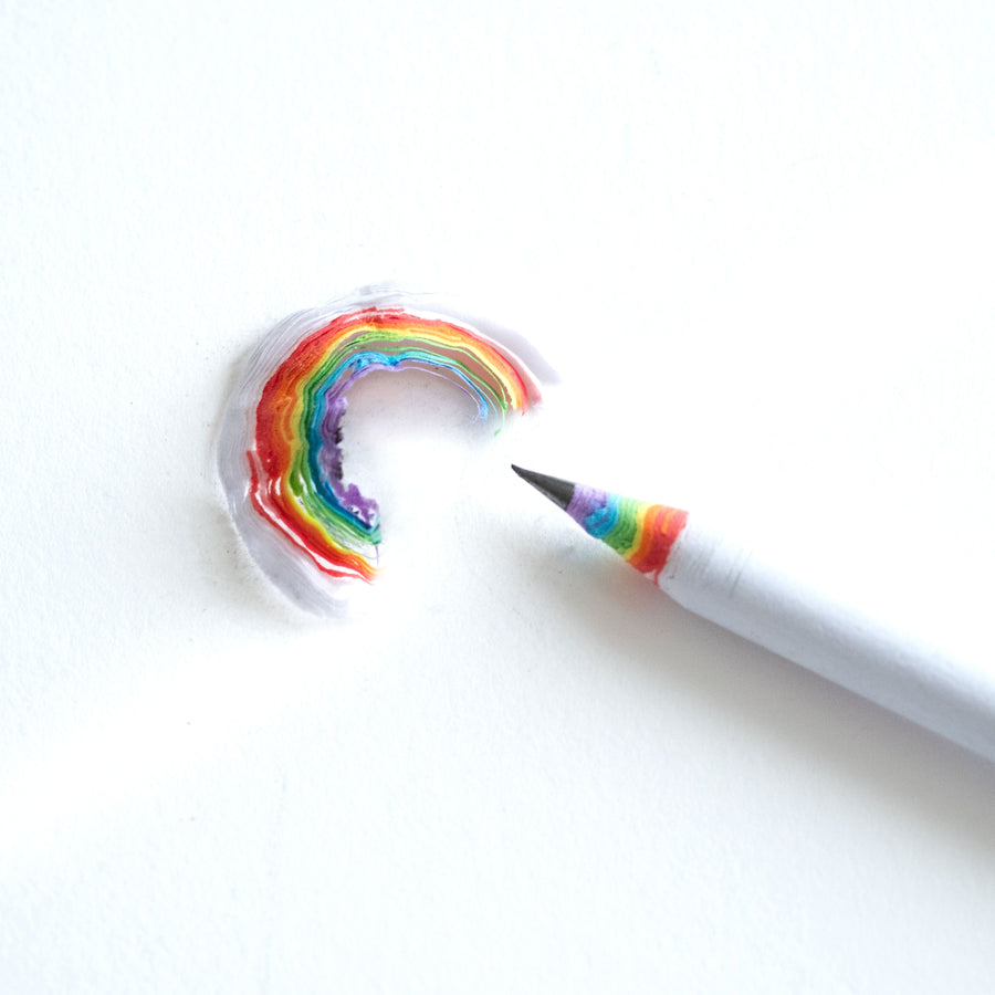 Rainbow pencil with a sharpened lead and a wood shaving fro the pencil showing the rainbow