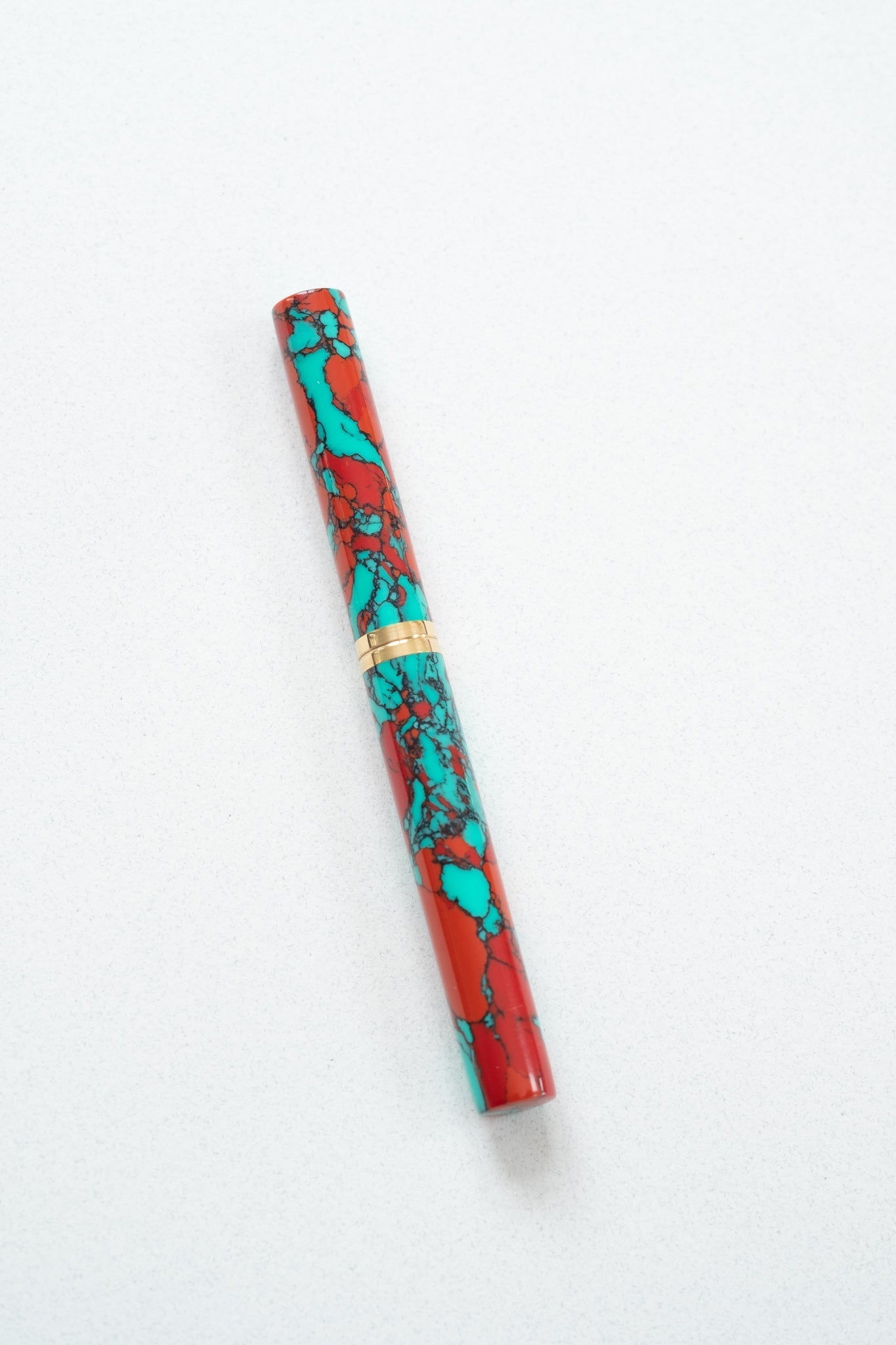 A red jasper Studio pen on a white desk with the lid on