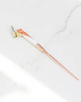 A rose gold and white oblique hand made calligraphy pen with a copper tail