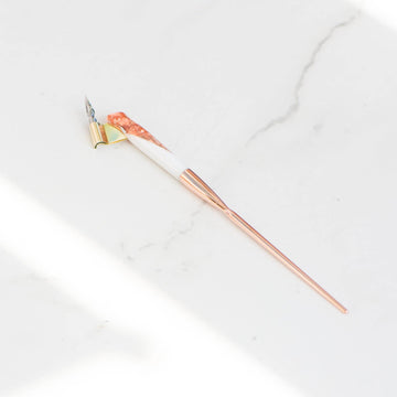 A rose gold and white oblique hand made calligraphy pen with a copper tail