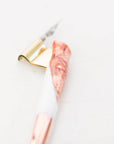 A close up showing the detail on the grip of a rose gold and white oblique hand made calligraphy pen with a copper tail