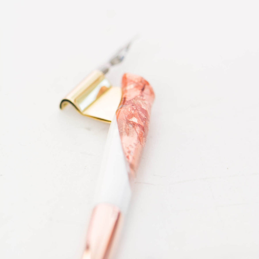 A close up showing the detail on the grip of a rose gold and white oblique hand made calligraphy pen with a copper tail