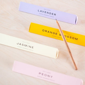 A scented pencil resting on the prism box packaging with the four different scents on display