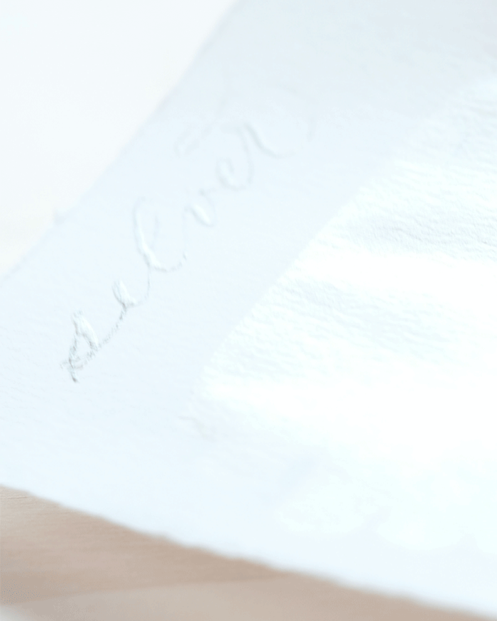 Silver calligraphy writing on a sheet of paper